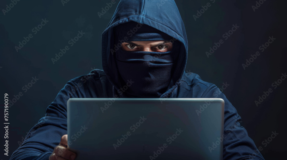 A faceless hacker in a dark blue hoodie is operating a laptop, with a focus on anonymity and digital security A faceless hacker in a dark blue hoodie is operating a laptop, with a focus on anonymity and digital security