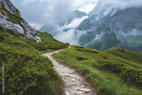 A scenic path cutting through a grassy area with majestic mountains in the distance, Rugged mountain path leading to a hidden valley, AI Generated photo