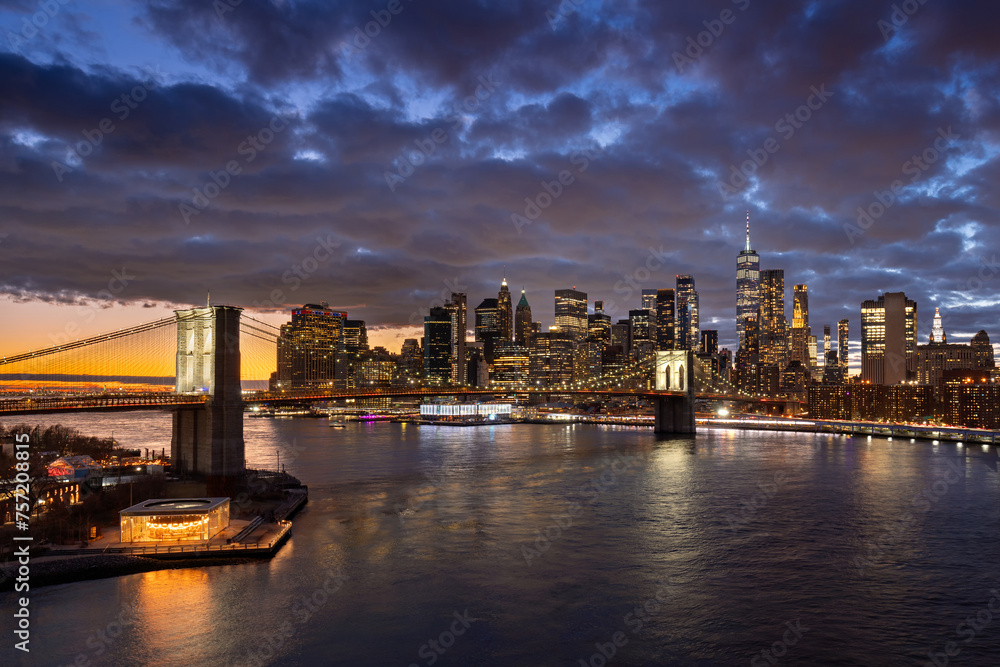 Brooklyn Bridge and waterfront with the East River. Dumbo, and Lower Manhattan illuminated skyscrapers at twilight, New York City