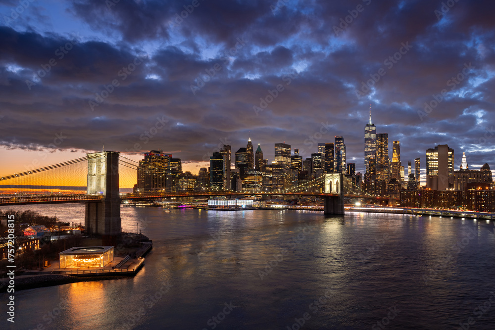Brooklyn Bridge and waterfront with the East River. Dumbo, and Lower Manhattan illuminated skyscrapers at twilight, New York City Brooklyn Bridge and waterfront with the East River. Dumbo, and Lower Manhattan illuminated skyscrapers at twilight, New York City