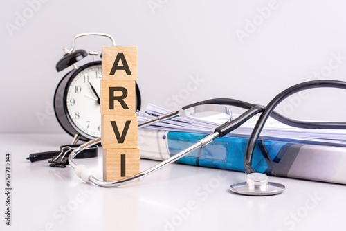 text ARVI is written on wooden cubes near a stethoscope on a paper background. medical concept. ARVI - short for Acute Respiratory Viral Infection photo