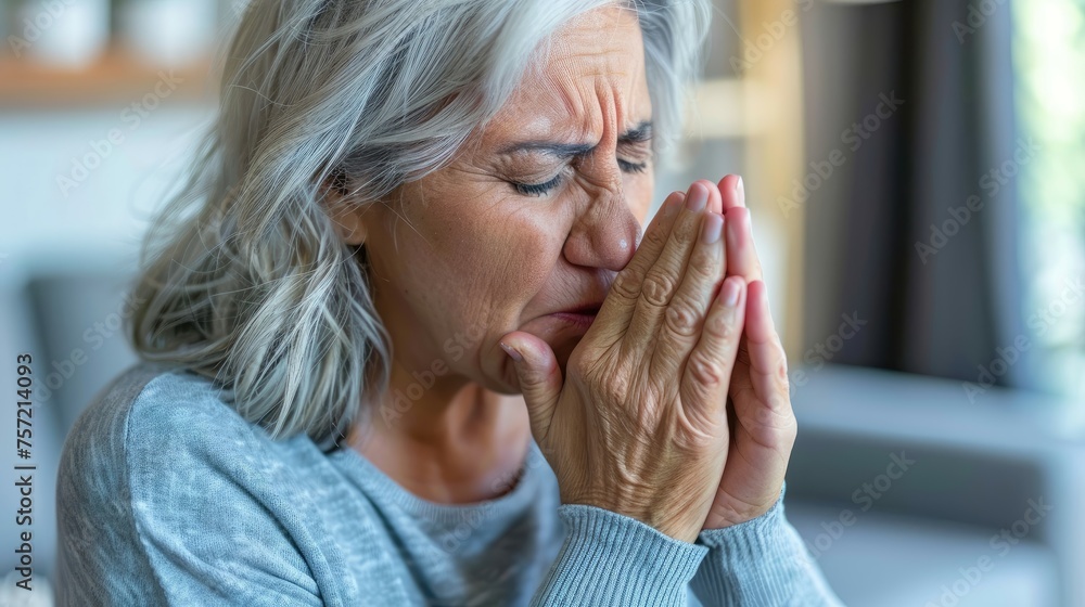 Mature woman sneezing into her hands, eyes closed. Mature woman sneezing into her hands, eyes closed.