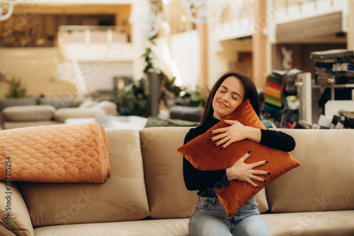 Portrait of young woman choosing pillow at store of household goods