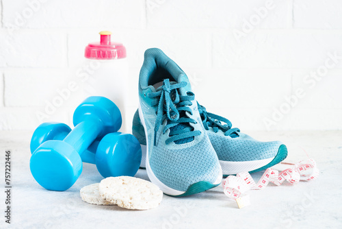 Fitness background on white. Sneakers, dumbbells, towel and diet food. Fitness, workout and diet concept.