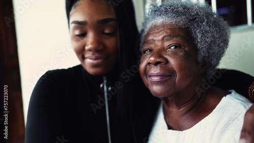 African American granddaughter hugging elderly 80s grandmother showing support and help for inter-generational family member. Family unity and love during old age