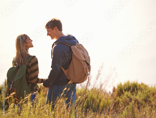 Love, holding hands and couple hiking in nature for travel, backpack or communication while bonding. Happy, adventure or people speaking in countryside for field trip, vacation or exploration journey