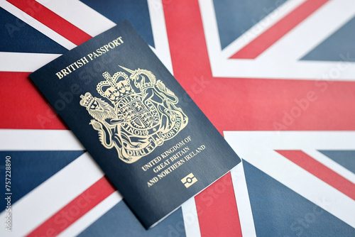 Blue British passport on national flag background close up. Tourism and citizenship concept