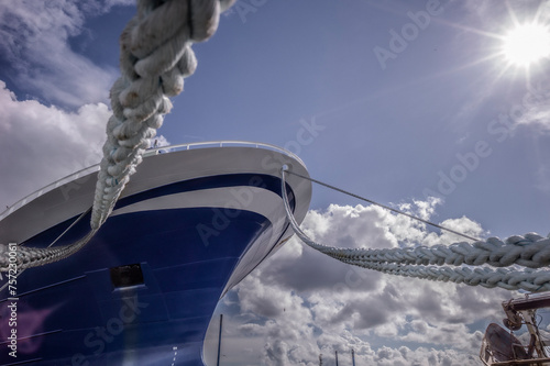 A ship moored under a sunny sky, viewed through the sturdy ropes that secure it photo
