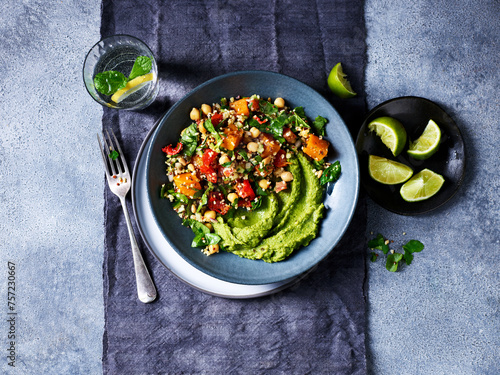 A vibrant green avocado puree topped with a colorful quinoa salad on a stylish plate.
