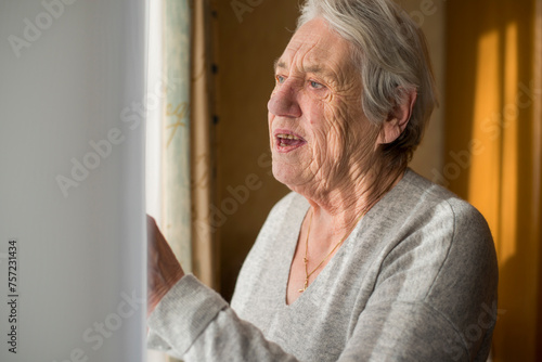 Elderly person gazing outside with a thoughtful expression. photo