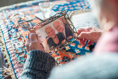 Elderly hands holding a treasured photo frame with an image of an older couple photo
