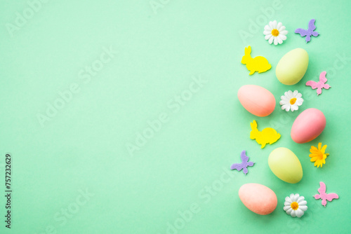 Happy Easter background. Eggs, rabbit, spring flowers and butterfly. Flat lay image at green background. © nadianb