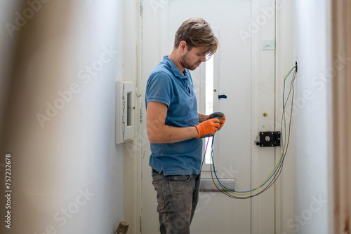 A focused technician working on electrical wiring at home. photo