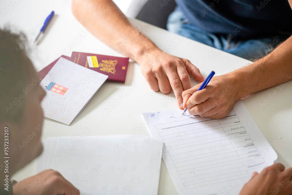 Two individuals engaged in paperwork at a white table. Two individuals engaged in paperwork at a white table.