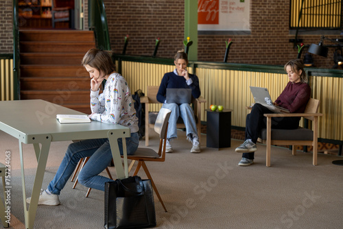 Three students focused on their work in a modern study hall. photo
