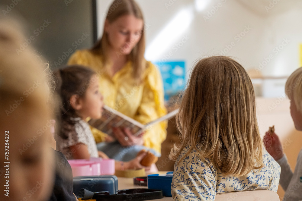 A teacher engaging with young students during storytime in a bright classroom setting. A teacher engaging with young students during storytime in a bright classroom setting.