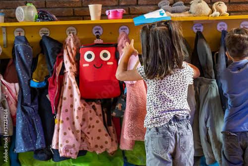 Little girl choosing her backpack from a colorful kindergarten cloakroom. photo