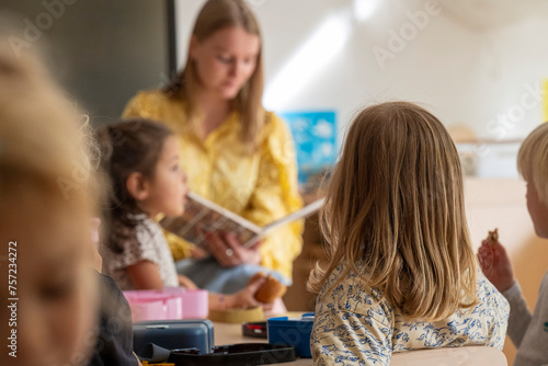A teacher engaging with young students during storytime in a bright classroom setting. photo