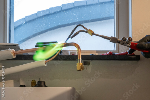 Sparks fly as a professional works on plumbing under a bright window. photo