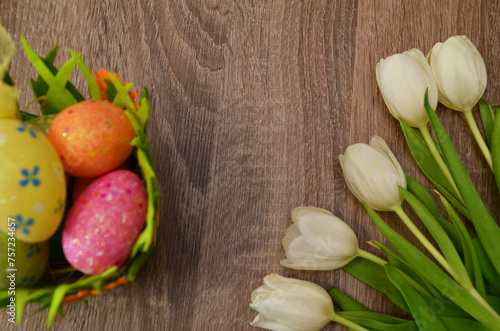 Easter concept. easter eggs in bowl ceramic easter bunnies yellow and pink tulips on isolated light beige background