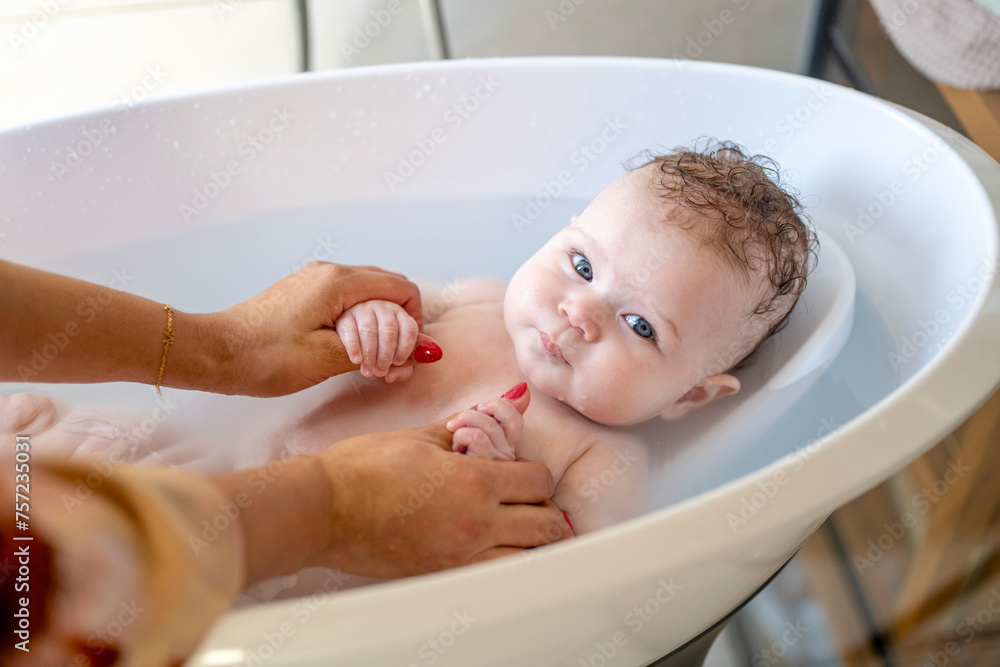 Baby enjoying a gentle bath with caring hands holding them steady. Baby enjoying a gentle bath with caring hands holding them steady.