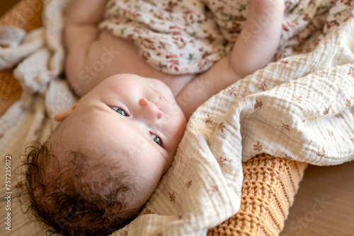 Baby relaxed on a cozy blanket gazing upwards with interest. photo