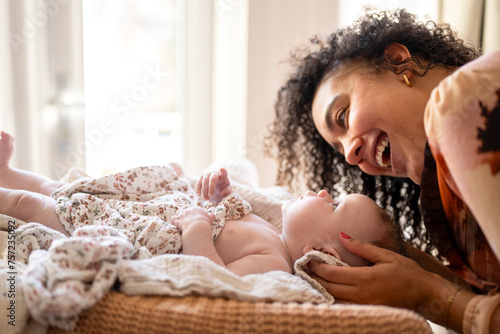 A joyful moment as a mother interacts with her baby lying in a cozy home setting. photo