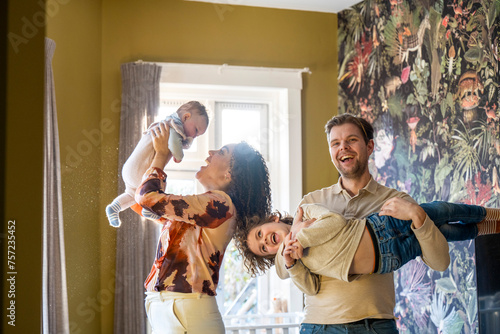 Family fun time as a parent lifts a joyful child into the air in a cozy home setting. photo
