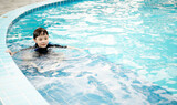 A little asian boy in swimming in the pool. Cute kids playing in outdoor swimming pool on a hot summer day. Kids learn to swim.