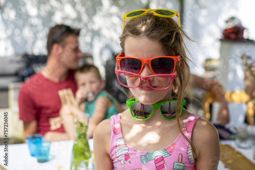Girl wearing multiple pairs of colorful sunglasses photo