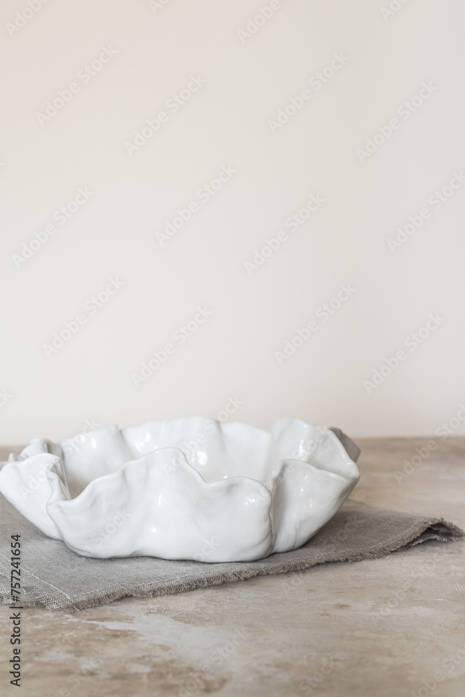 white ceramic plate with an uneven edge on a linen napkin. Side view. Mockup. white ceramic plate with an uneven edge on a linen napkin. Side view. Mockup.