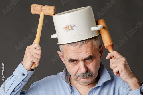 A perplexed man with a saucepan on his head is trying to find the right thoughts with the help of a hammer and rolling pin.