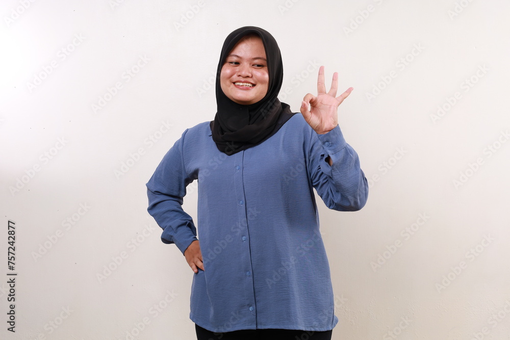 Asian muslim woman standing while making okay hand gesture Asian muslim woman standing while making okay hand gesture