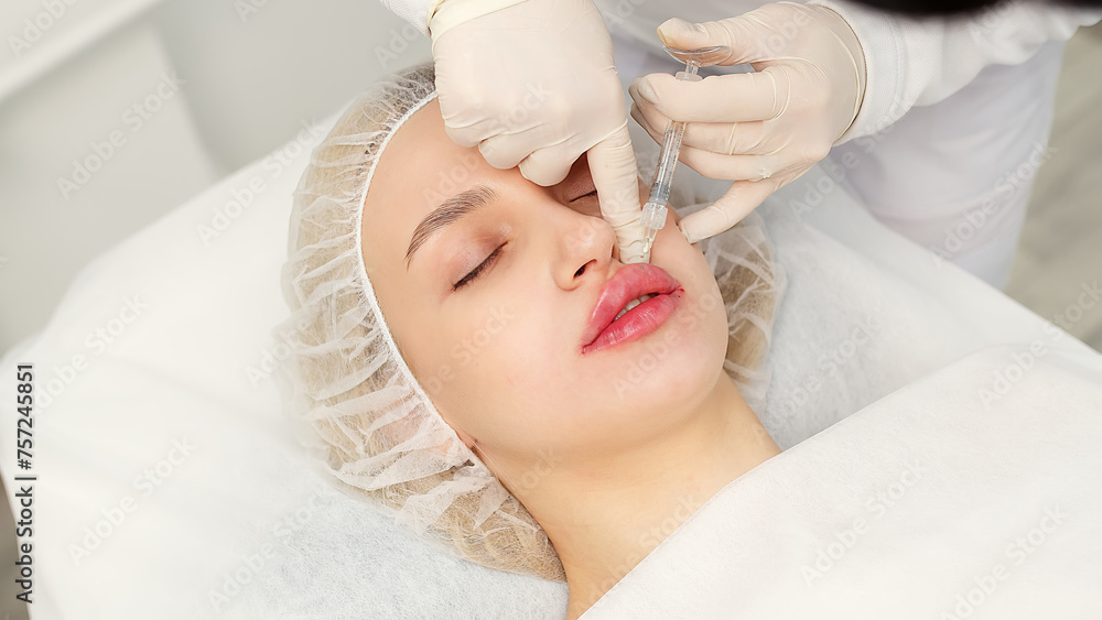 Injection procedure for lip augmentation, close-up. The cosmetologist slowly and carefully injects filler into the client’s lips. Advertising concept for facial care, youth and beauty. Injection procedure for lip augmentation, close-up. The cosmetologist slowly and carefully injects filler into the client’s lips. Advertising concept for facial care, youth and beauty.