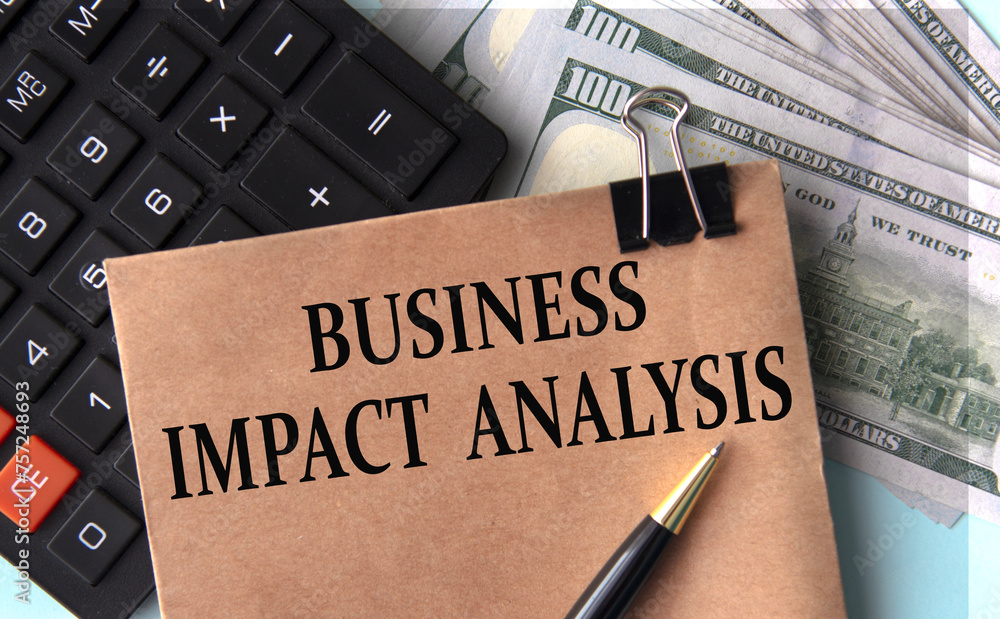 BUSINESS IMPACT ANALYSIS - words on brown paper on the background of calculator and banknotes