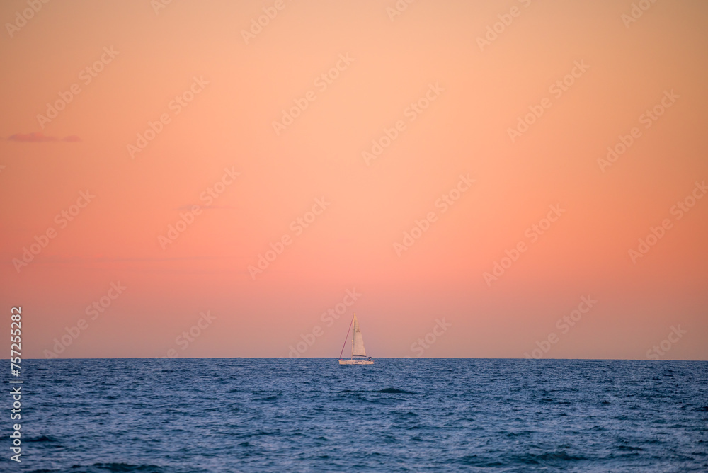 Un bateau à voile seul en mer au coucher de soleil