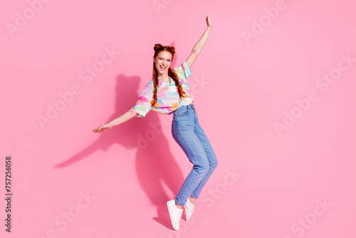 Full size photo of carefree eccentric funny girl dressed colorful blouse jeans standing on tiptoes isolated on pink color background