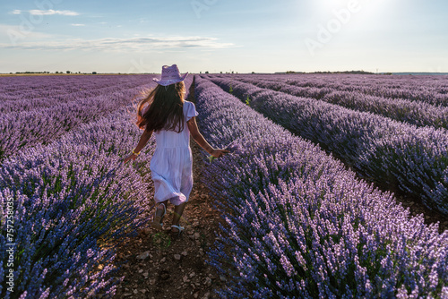 Young girl running between lavender bushes in the field. Brihuega, Spain.