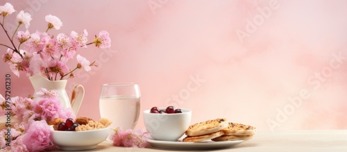 Breakfast with pancakes, milk and cherry blossom on pink background