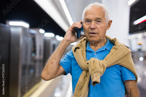 Old man with smartphone in subway station