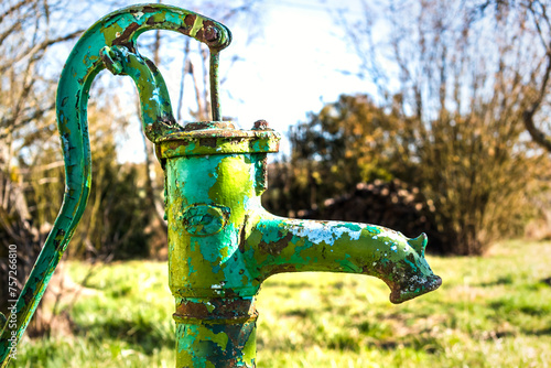 Old hand water pump on a well in the garden, watering and saving water, rural environnement photo