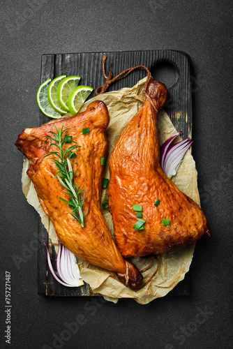 Baked chicken legs on a wooden board. Grilled chicken, grilled chicken legs. On a dark background.