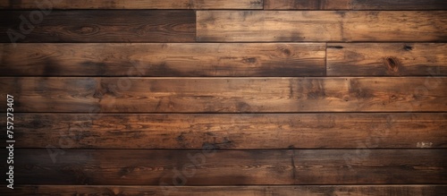 A closeup of a brown hardwood plank wall with a blurred background. The rectangular pattern showcases the natural tints and shades of the wood stain, making it a beautiful building material