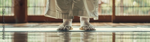 Person practicing Aikido wearing traditional keikogi and tabi shoes on tatami mat