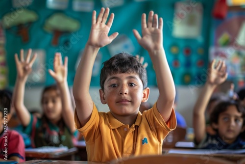 Elementary age student boy raised hands up in class. Volunteering and participating classroom concept. © Straxer