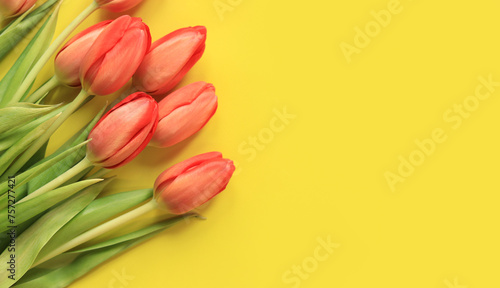 Fototapeta Naklejka Na Ścianę i Meble -  A bouquet of pink tulips lies on a yellow background, top view. Flowers for banners and cards. Bouquet for Mother's Day or other holiday. Tulips on a bright background with copy space