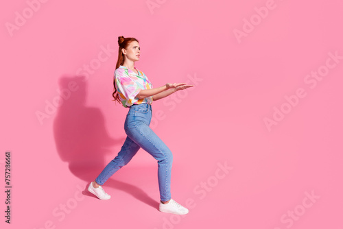 Full size photo of gloomy serious girl dressed colorful blouse jeans hold heavy object look empty space isolated on pink color background