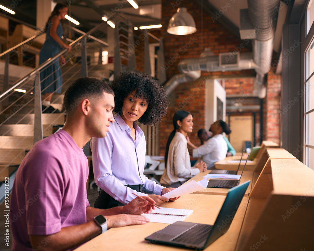Male And Female Businesspeople Meeting In Office Discussing Documents With Colleagues In Background Male And Female Businesspeople Meeting In Office Discussing Documents With Colleagues In Background