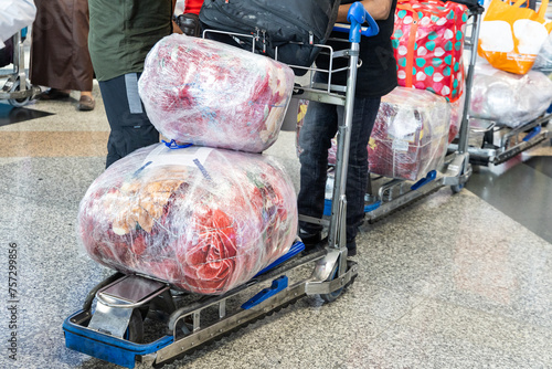 Traveler at airport with luggages on trolley wrapped with protective film for safety