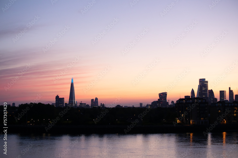 Pink, purple and orange striped radiatus altostratus clouds cover the sky over the London skyline at sunset.